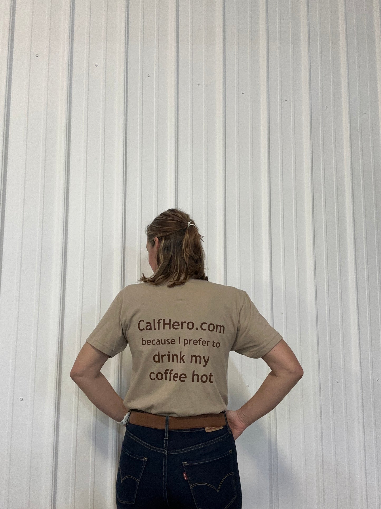 A person wearing a CalfHero.com shirt, facing away from the camera. Calf Hero shirt funny calf-inated with a cup of coffee with an image of a calf on on the coffee mug.